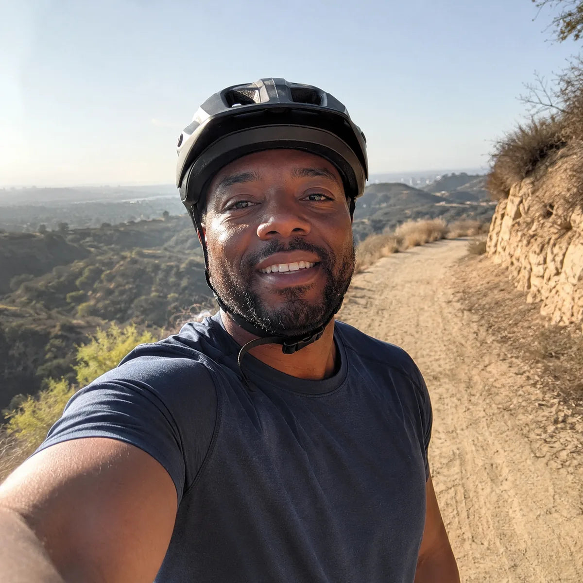 Black male cyclist taking a casual outdoor selfie on a scenic trail